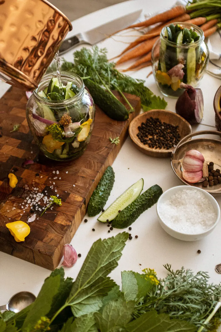 view of fresh ingredients for pickling cucumbers with herbs and spices on a wooden cutting board.